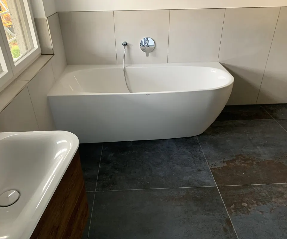 Saniertes Bad mit freistehender Wanne und dunklem Natursteinboden