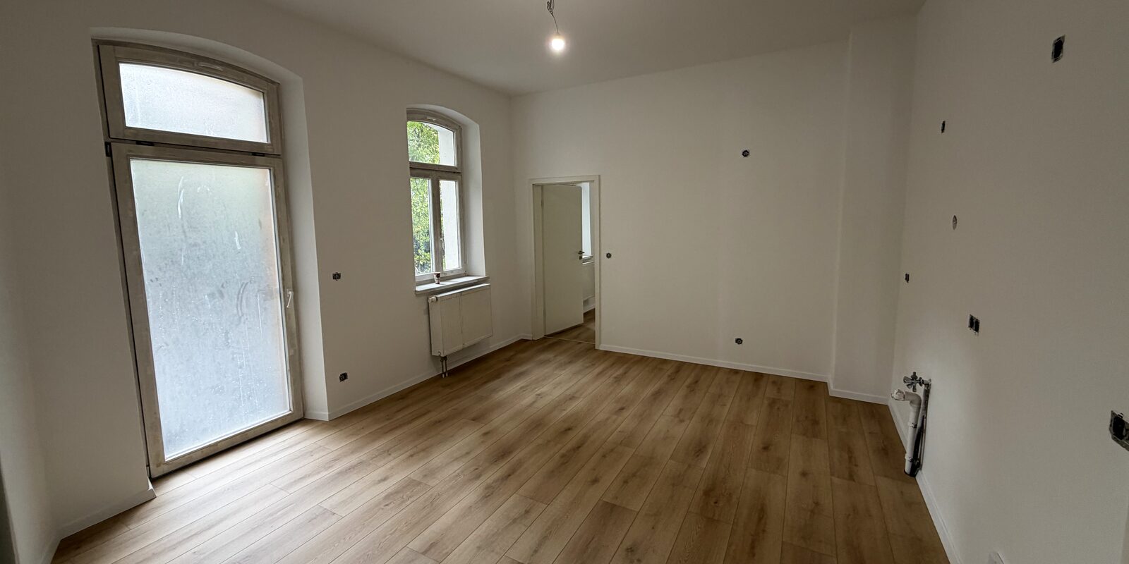 Kernsanierter Altbauraum mit Bogenfenstern und neuem Boden
