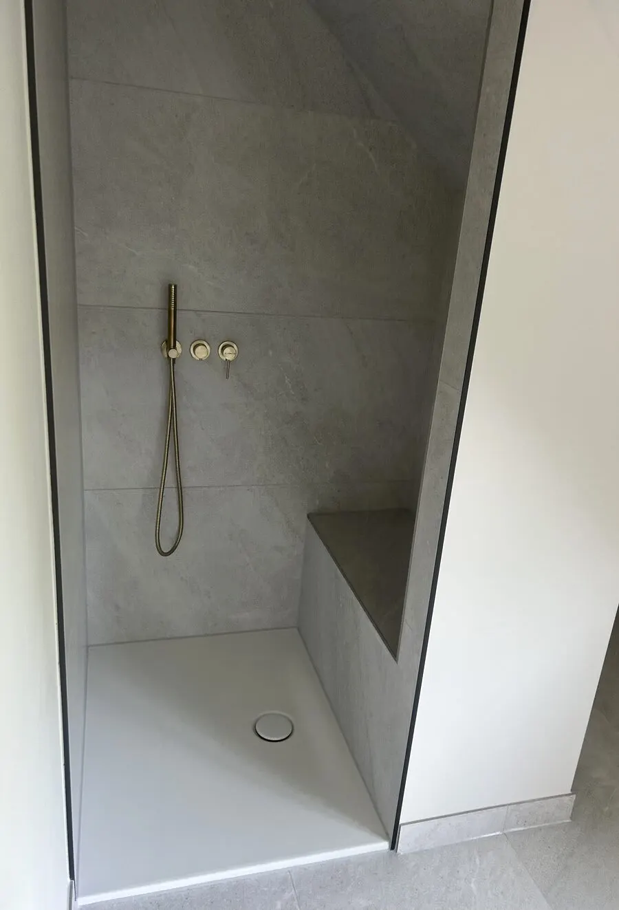 Sanierte Dusche mit Naturstein-Fliesen und goldener Armatur