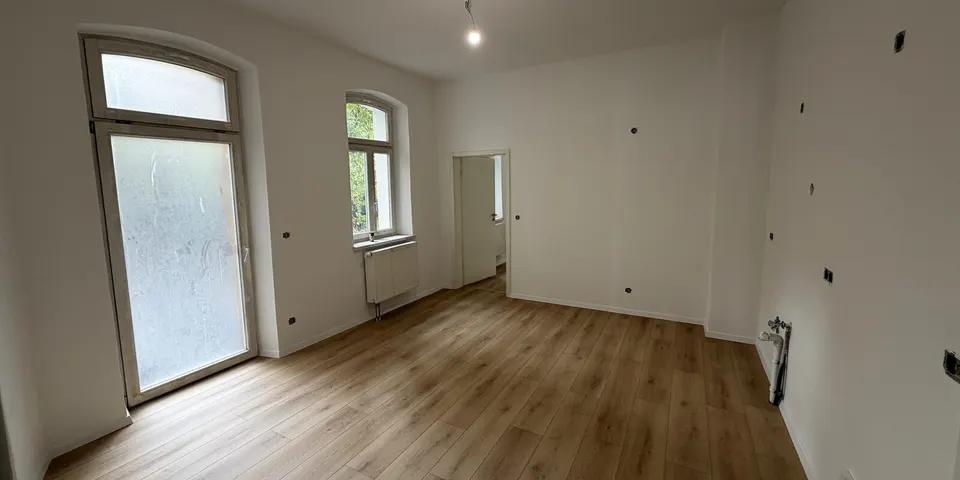 Kernsanierter Altbauraum mit Bogenfenstern und neuem Boden